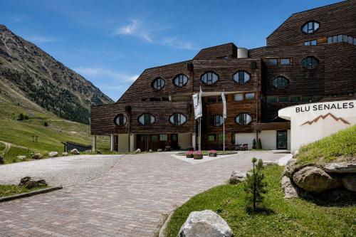 a large wooden building with windows on a mountain at Blu Senales Active & Family Resort in Maso Corto