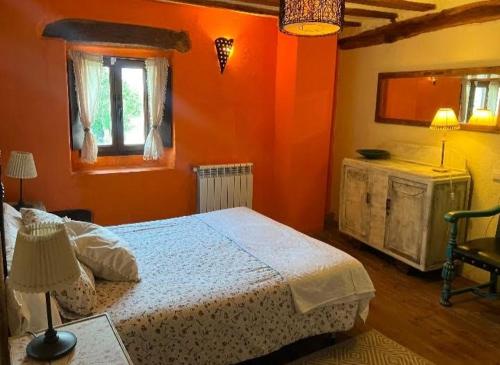 a bedroom with a bed and an orange wall at Urbasako Argizar Etxea in Larraona