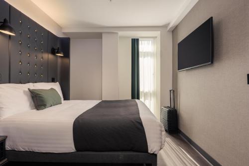 a bedroom with a bed and a television on the wall at Point A Hotel Edinburgh St Andrew Square in Edinburgh