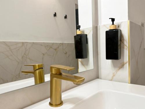 a bathroom sink with a gold faucet and a mirror at Tiny House nel cuore del Monferrato in Conzano
