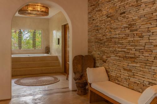 a bathroom with a brick wall and a tub at Villa Paz - La Villa Group in Camocim