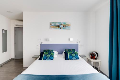 a bedroom with a large white bed with blue pillows at Hôtel Saint Albert in Sarlat-la-Canéda