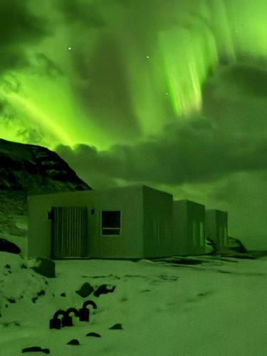a group of buildings under a green sky at Kirkjufell View Cottages in Grundarfjordur