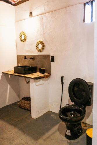 a bathroom with a black toilet in a room at Alto Saudade - Atins in Barreirinhas