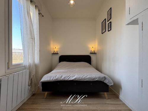 a bed in a bedroom with two lamps on the wall at L'Arche in Saint-Dizier