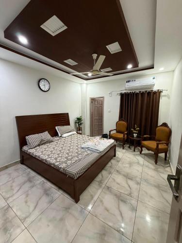 a bedroom with a bed and two chairs and a clock at Khushal Residence in Peshawar