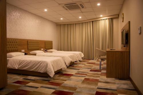 a hotel room with four beds and a television at Rawaz Hotel in As Sulaymānīyah