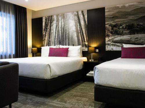 a hotel room with two beds and a painting on the wall at Mercure Tamworth in Tamworth