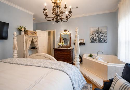 a bedroom with a bed and a tub and a chandelier at Historic Mansion-King Suite-The Blue Jay in Fort Smith
