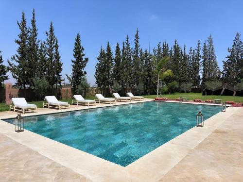 a swimming pool with chaises and chairs in a yard at Villa zitoun in Aït Bou Zguia