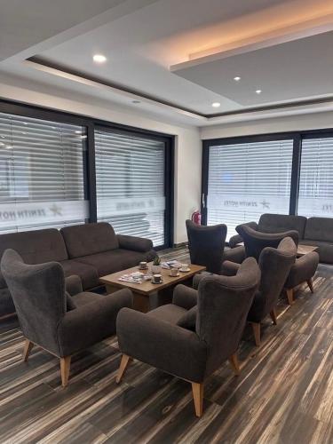 a waiting room with a couch and chairs and windows at Zenith Hotel Frankfurt Airport in Kelsterbach