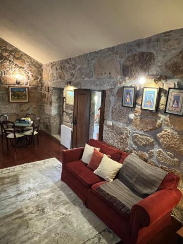 a living room with a red couch in a stone wall at Casa da Costeira in Figueiró