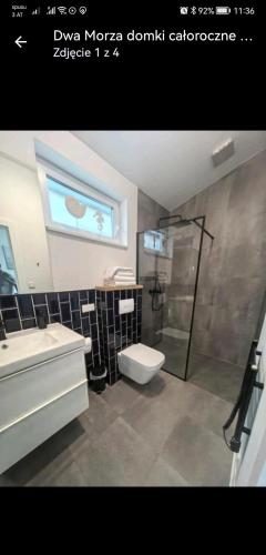 a bathroom with a sink and a toilet and a shower at Dwa Morza domki całoroczne z ogrodem in Puck