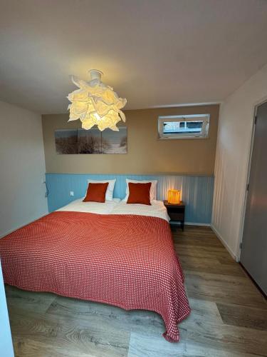 a bedroom with a red bed and a chandelier at Appartement Moustache in Goes