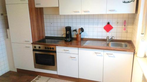 een kleine keuken met witte kasten en een wastafel bij Ferienwohnung Familie Perl in Immenhausen