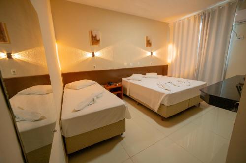 a hotel room with two beds and a mirror at Hotel Dan Inn Express Foz do Iguaçu By Nacional Inn in Foz do Iguaçu