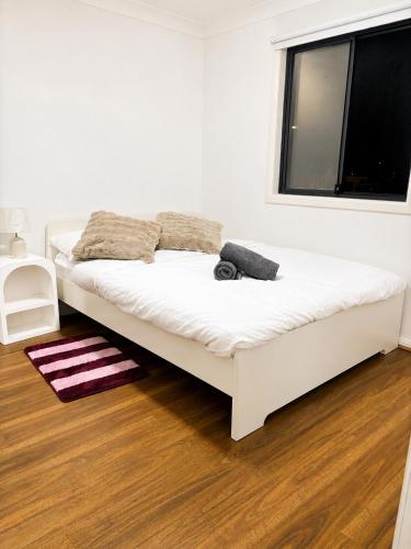 a white bed in a room with a window at 21A Armstrong Place in Schofields