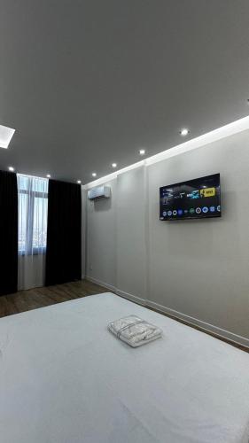 a bedroom with a bed with a tv on the wall at Lux Apart in Khujand