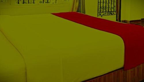 a bed with a red and white blanket on it at The Nagpal Hotel in Haridwār