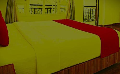 a large bed with a red and white blanket on it at The Nagpal Hotel in Haridwār