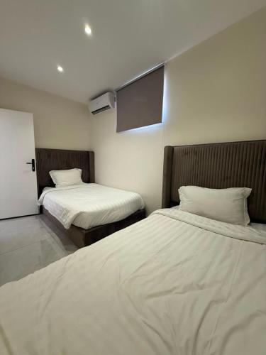 a room with two beds with white sheets at أجنحة السمو in Hail