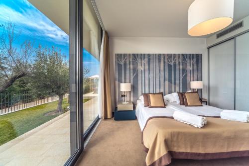 a bedroom with two beds and a large window at Golden Rays Luxury Villas & Apartments in Primošten
