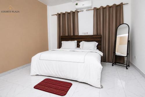 a bedroom with a large white bed and a mirror at Courts Plaza Apartments in Bawaleshi