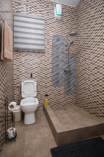 a bathroom with a shower and a toilet and a tub at Courts Plaza Apartments in Bawaleshi