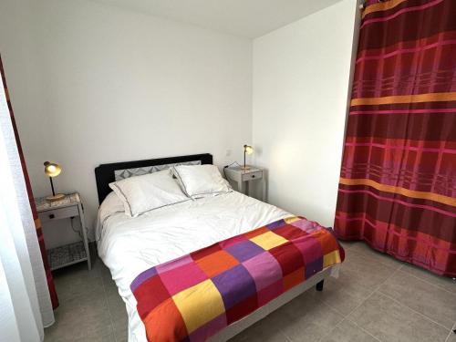 a bedroom with a bed with a colorful blanket on it at Détente à deux in Saint-Martin-de-Seignanx