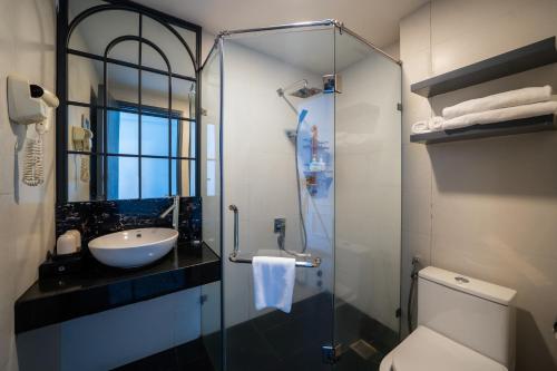 a bathroom with a sink and a toilet and a glass shower at Le House Boutique Hotel - 100m to the beach in Danang