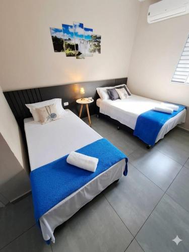 two beds in a room with a table at Studio Cataratas com garagem e ar condicionado in Foz do Iguaçu