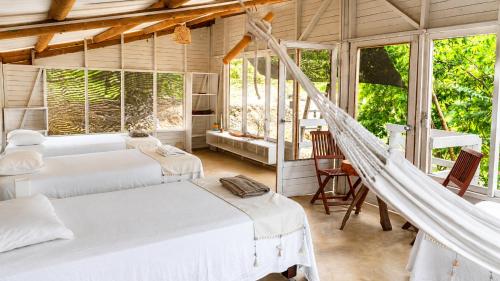 a room with four beds and a hammock in it at Hotel Fuerte Mayal in Puerto Limón