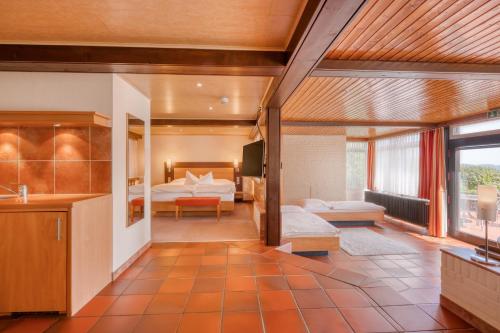a large living room with a bed and a bedroom at Hotel Wiehen-Therme in Hüllhorst