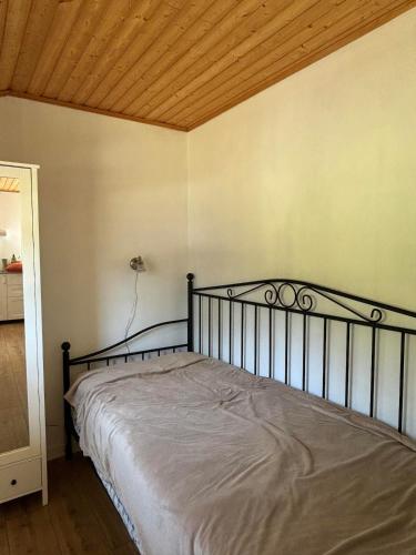 a bed in a bedroom with a wooden ceiling at Cozy cottage on Värmdö in Djurhamn