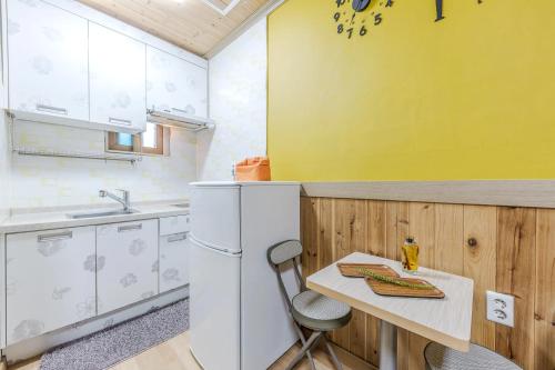a kitchen with a table and a yellow wall at Suncheonman Muhan Dojan Pension in Suncheon