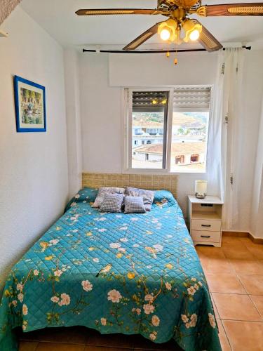 a bedroom with a bed with a green comforter at El Paraíso del Tesorillo in Almuñécar