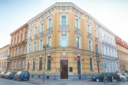 un gran edificio amarillo con coches estacionados frente a él en Cuba Bar & Hostel, en České Budějovice