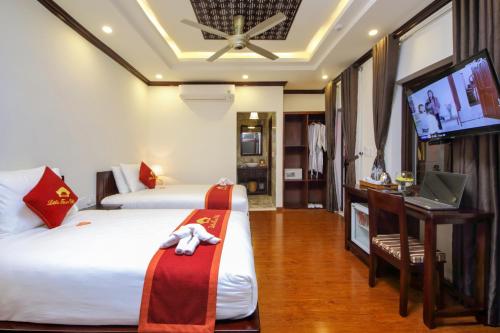 a hotel room with two beds and a tv at Little Town Villa in Hoi An
