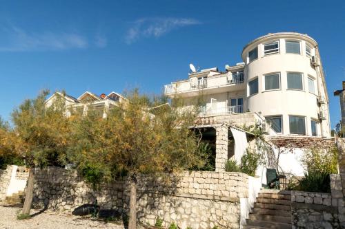 a large white building behind a stone wall at Apartments Beach house Blace in Blace