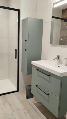 a white bathroom with a sink and a shower at Gîte La Ferme Ecole in Perrou