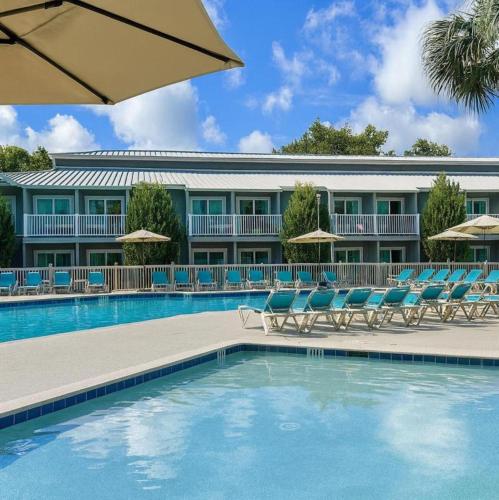 a hotel with a swimming pool with chairs and an umbrella at Players Club Resort in Hilton Head Island