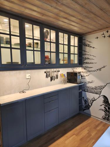 a kitchen with blue cabinets and a wall with birds on it at Muminhuset i Norberg in Norberg
