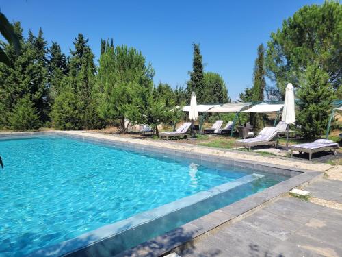 a swimming pool with chairs and umbrellas in a yard at Villa Blanche - Teritoria in Arles