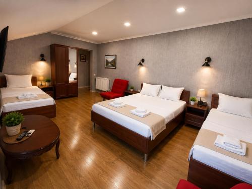 a hotel room with two beds and a red chair at Hotel Kalanga in Tbilisi City