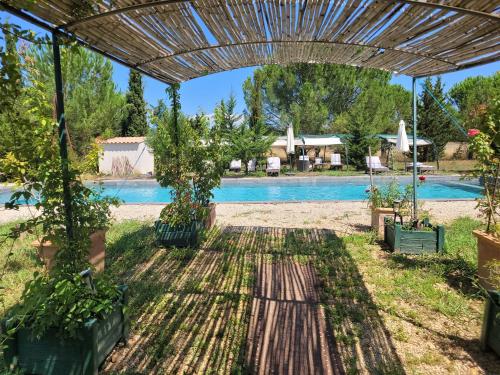 a pergola with potted plants and a swimming pool at Villa Blanche - Teritoria in Arles