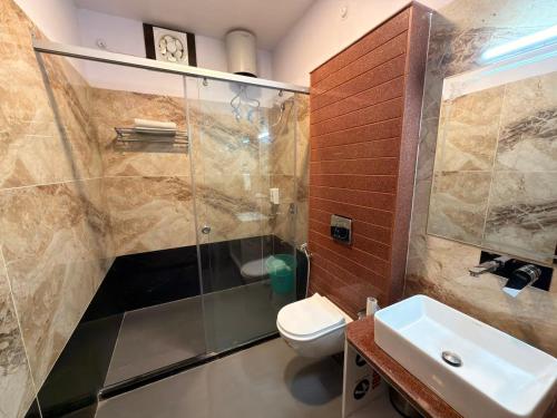 a bathroom with a shower and a toilet and a sink at Chauhan Sheraton Resort in Pushkar