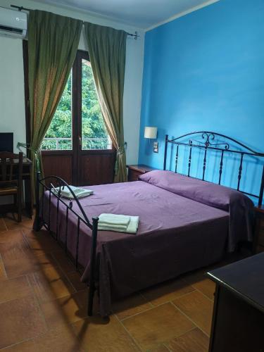 a bedroom with a bed with purple sheets and a blue wall at Al Giumani in Mammola