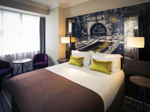 a hotel room with a large bed with yellow pillows at Mercure Oxford Eastgate Hotel in Oxford