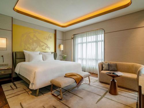 a bedroom with a large white bed and a couch at Pullman Hanoi in Hanoi