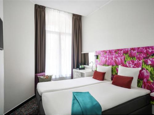 a hotel room with a large bed with a purple headboard at ibis Styles Amsterdam City in Amsterdam